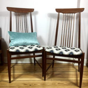 Midcentury modern Esszimmerstühle mit hoher Lehne aus Teakholz. Die Stühle stammen aus Skandinavien. Bezogen wurden die Stühle mit einem gewebten Jacquard Stoff in einem weiss, beige marineblauem Bohemian Muster in abwechselnder Rhombenform. Die hohen Lehnen der Stühle haben am Rückenteil 6 schmale, hochverlaufende Streben, die in zwei breitere Streben eingefasst nach oben in einem schiffchenähnlichem Oberteil enden.