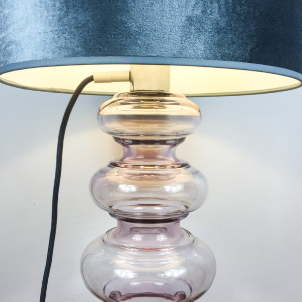 Eine sehr schöne Lampe mit einem Glaskorpus aus leicht rosé getöntem Glas. Trotz ihrer Größe vermittelt die Lampe Leichtigkeit. Der Schirm ist aus taupe-farbenem Samt. Der Korpus besteht aus 6 Glasringe, oder Ausbuchtungen, die sich von unten nach oben verjüngen, also schmaler werden.