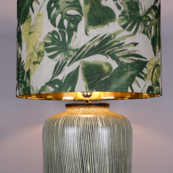 Die Lampe Botanical war ursprünglich eine Vase aus den 50er Jahren. Mit ihrem senkrecht verlaufenden Streifendesign in einem blassen Gelb und Grau, spiegelt die Vase die 50er Jahre wieder. Durch meine Idee, einen Deckel zu konstruieren, der die Gewindestange für den Lampenschirm als auch die Elektrik beinhaltet, kann die ehemalige Vase nun als Lampe erstrahlen. Der Lampenschirm ist mit seinem floralen Blattdesign sehr erfrischend. Für den kommenden Frühling ein Hingucker. Die goldenen Innenseite des Schirmes gibt ein schönes, warmes Licht ab.Die Lampe kann auch als Vase verwendet werden, da der Deckel nur in die Vase eingelassen ist. Wenn Sie eine kleine Wohnung haben und der Besuch bringt einen Blumenstrass mit, dann können Sie die Lampe zur Vase umfunktionieren.