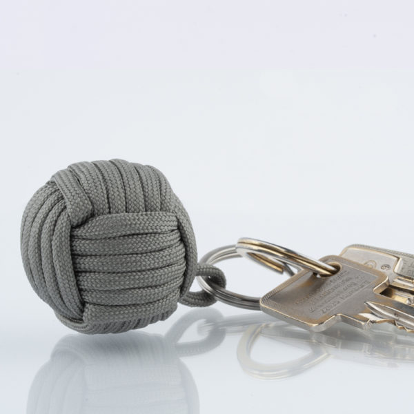 Seglerknoten Affenfaust. Ein Schlüsselanhänger aus einem grauen Paracordseil. Ein DIY Produkt. Der Schlüsselanhänger ist mit einem 3,2cm großen Edestahlfederring versehen. Die Affenfaust hat einen Durchmesser von 3,7cm.