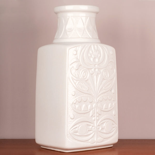 Die Bodenvase von der Firma Eduard Bay GmbH stammt aus den 1960er Jahren. Sie ist vintage. Also original aus der Zeit. Ihr Zustand ist gut. Die Farbe weiss ist edel. Das florale, typische Muster (es erinnert an die Wandmalereien und Bildhauerkunst der Inkas), das Bodo Mans als Designer verwendet hat, gibt es in verschiedenen Farbkombis. Diese Vase in weisser Optik ist sehr edel. Die Form, der Vase deutet eine Trapezform an. Unten ist die Vase breiter und verläuft verjüngend nach oben und endet im Vasenhals, der ganz oben eine kleine Krempe hat. Zur Info: Oben am Hals ist ein kleiner Sprung in der Lasur, der jedoch nur das Alter dieser schönen Vase widerspiegelt und fällt kaum auf, insbesondere gar nicht, wenn große, schöne Blumen in der Vase sind. Die Bodenvase, kann aber auch als Tischvase genommen werden. Gerade, bei der Größe der Vase, fällt sie optisch auf und ist ein Eye-Catcher und setzt damit ein Statement in Deinem zu Hause. Sei mutig und setze Akzente.