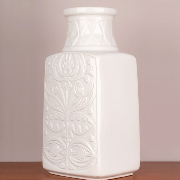 Die Bodenvase von der Firma Eduard Bay GmbH stammt aus den 1960er Jahren. Sie ist vintage. Also original aus der Zeit. Ihr Zustand ist gut. Die Farbe weiss ist edel. Das florale, typische Muster (es erinnert an die Wandmalereien und Bildhauerkunst der Inkas), das Bodo Mans als Designer verwendet hat, gibt es in verschiedenen Farbkombis. Diese Vase in weisser Optik ist sehr edel. Die Form, der Vase deutet eine Trapezform an. Unten ist die Vase breiter und verläuft verjüngend nach oben und endet im Vasenhals, der ganz oben eine kleine Krempe hat. Zur Info: Oben am Hals ist ein kleiner Sprung in der Lasur, der jedoch nur das Alter dieser schönen Vase widerspiegelt und fällt kaum auf, insbesondere gar nicht, wenn große, schöne Blumen in der Vase sind. Die Bodenvase, kann aber auch als Tischvase genommen werden. Gerade, bei der Größe der Vase, fällt sie optisch auf und ist ein Eye-Catcher und setzt damit ein Statement in Deinem zu Hause. Sei mutig und setze Akzente.