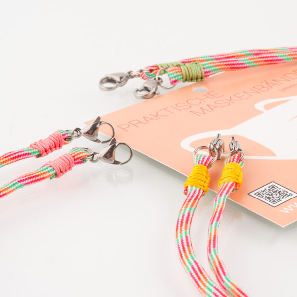 Das Maskenband ist der kleine Helfer im Alltag. Hier in der Farbkombi grün orange rot und pink. Damit Du nicht ständig Deine Maske aus der Tasche holen musst, oder in der Hand hältst, hängst Du die Maske mit dem Band einfach um den Hals, oder steckst sie Dir in die Tasche Deines Oberhemdes, oder in die Tasche Deiner Jacke, wenn Du sie nicht benötigst. Sie kann aber auch einfach runterhängen. Ob Du bei der Arbeit bist, in ein Geschäft, oder ins Restaurant gehst, Du kannst sie schnell aufsetzen. Sogar mit einer Hand ist das möglich. Die zwei Karabinerverschlüsse klemmst Du einfach an das Gummiband, das bei Gebrauch um die Ohren gelegt wird. Durch das Eigengewicht hängen die Karabiner an der tiefsten Stelle des Gummibandes, sodaß sie auch nicht an den Ohren drücken können. Die Maskenbänder werden mit Deinem Farbwunsch angefertigt. Wähle Deine Wunschfarbe für die Bänder, die die Karabiner halten, im Menü aus.