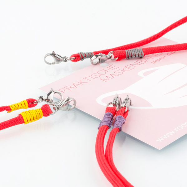 Das Masken Band ist der kleine Helfer im Alltag. Hier in der Farbkombi orange und lila. Damit Du nicht ständig Deine Maske aus der Tasche holen musst, oder in der Hand hältst, hängst Du die Maske mit dem Band einfach um den Hals und steckst sie Dir in die Tasche Deines Oberhemdes, oder in die Revertasche Deiner Jacke, wenn Du sie nicht benötigst. Sie kann aber auch einfach runterhängen. Ob Du bei der Arbeit bist, in ein Geschäft, oder ins Restaurant gehst, Du kannst sie schnell aufsetzen. Sogar mit einer Hand ist das möglich. Die zwei Karabinerverschlüsse klemmst Du einfach an das Gummiband, das bei Gebrauch um die Ohren gelegt wird. Durch das Eigengewicht hängen die Karabiner an der tiefsten Stelle des Gummibandes, sodaß sie auch nicht an den Ohren drücken können. Die Maskenbänder werden mit Deinem Farbwunsch angefertigt. Wähle Deine Wunschfarbe für die Bänder, die die Karabiner halten, im Menü aus.