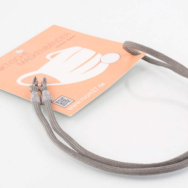 Das Masken Band ist der kleine Helfer im Alltag. Hier in der Farbkombi grau und beige. Damit Du nicht ständig Deine Maske aus der Tasche holen musst, oder in der Hand hältst, hängst Du die Maske mit dem Band einfach um den Hals und steckst sie Dir in die Tasche Deines Oberhemdes, oder in die Revertasche Deiner Jacke, wenn Du sie nicht benötigst. Sie kann aber auch einfach runterhängen. Ob Du bei der Arbeit bist, in ein Geschäft, oder ins Restaurant gehst, Du kannst sie schnell aufsetzen. Sogar mit einer Hand ist das möglich. Die zwei Karabinerverschlüsse klemmst Du einfach an das Gummiband, das bei Gebrauch um die Ohren gelegt wird. Durch das Eigengewicht hängen die Karabiner an der tiefsten Stelle des Gummibandes, sodaß sie auch nicht an den Ohren drücken können. Die Maskenbänder werden mit Deinem Farbwunsch angefertigt. Wähle Deine Wunschfarbe für die Bänder, die die Karabiner halten, im Menü aus.