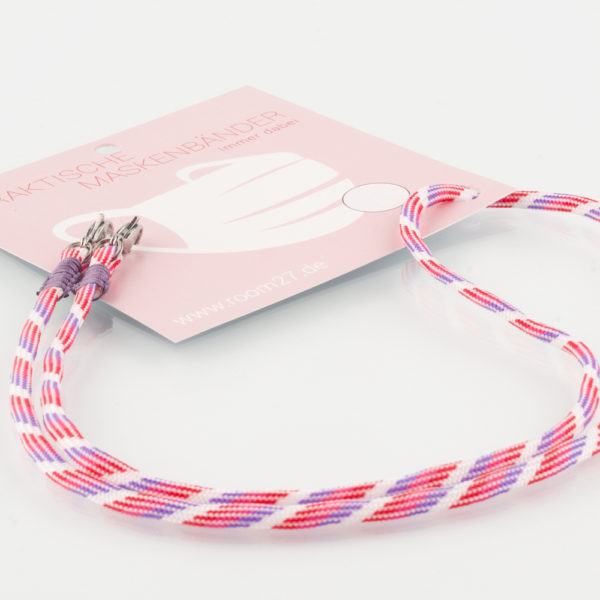 Das Maskenband ist der kleine Helfer im Alltag. Hier in der Farbkombi lila pink weiss und lila. Damit Du nicht ständig Deine Maske aus der Tasche holen musst, oder in der Hand hältst, hängst Du die Maske mit dem Band einfach um den Hals, oder steckst sie Dir in die Tasche Deines Oberhemdes, oder in die Tasche Deiner Jacke, wenn Du sie nicht benötigst. Sie kann aber auch einfach runterhängen. Ob Du bei der Arbeit bist, in ein Geschäft, oder ins Restaurant gehst, Du kannst sie schnell aufsetzen. Sogar mit einer Hand ist das möglich. Die zwei Karabinerverschlüsse klemmst Du einfach an das Gummiband, das bei Gebrauch um die Ohren gelegt wird. Durch das Eigengewicht hängen die Karabiner an der tiefsten Stelle des Gummibandes, sodaß sie auch nicht an den Ohren drücken können. Die Maskenbänder werden mit Deinem Farbwunsch angefertigt. Wähle Deine Wunschfarbe für die Bänder, die die Karabiner halten, im Menü aus.