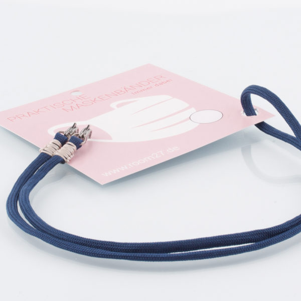 Das Masken Band ist der kleine Helfer im Alltag. Hier in der Farbkombi marineblau und beige. Eine klassische Farbe, die sich mit vielen Farben kombinieren lässt. Damit Du nicht ständig Deine Maske aus der Tasche holen musst, oder in der Hand hältst, hängst Du die Maske mit dem Band einfach um den Hals und steckst sie Dir in die Tasche Deines Oberhemdes, oder in die Revertasche Deiner Jacke, wenn Du sie nicht benötigst. Sie kann aber auch einfach runterhängen. Ob Du bei der Arbeit bist, in ein Geschäft, oder ins Restaurant gehst, Du kannst sie schnell aufsetzen. Sogar mit einer Hand ist das möglich. Die zwei Karabinerverschlüsse klemmst Du einfach an das Gummiband, das bei Gebrauch um die Ohren gelegt wird. Durch das Eigengewicht hängen die Karabiner an der tiefsten Stelle des Gummibandes, sodaß sie auch nicht an den Ohren drücken können. Die Maskenbänder werden mit Deinem Farb-Wunsch angefertigt. Wähle Deine Wunschfarbe für die Bänder, die die Karabiner halten, im Menü aus.