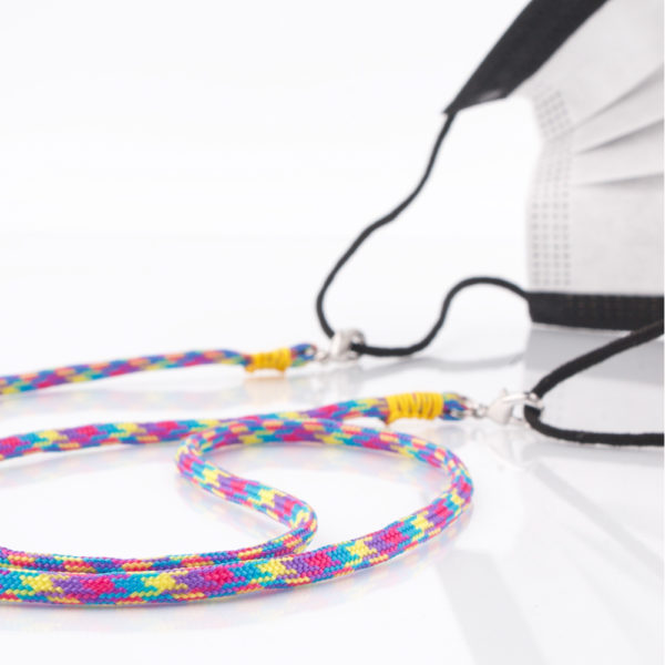 Das Maskenband ist der kleine Helfer im Alltag. Hier in der Farbkombi in Blau Pink Lila Gelb. Bunt ist für den Sommer immer perfekt. Sie passt sehr gut zu einer weissen Bluse, oder einem weissen Hemd. Damit Du nicht ständig Deine Maske aus der Tasche holen musst, oder in der Hand hältst, hängst Du die Maske mit dem Band einfach um den Hals und steckst sie Dir in die Tasche Deines Oberhemdes, oder in die Revertasche Deiner Jacke, wenn Du sie nicht benötigst. Sie kann aber auch einfach runterhängen. Ob Du bei der Arbeit bist, oder in ein Geschäft, oder ins Restaurant gehst, kannst Du sie schnell aufsetzen. Die zwei Karabinerverschlüsse klemmst Du einfach an das Gummiband, das bei Gebrauch um die Ohren gelegt wird. Durch das Eigengewicht hängen die Karabiner an der tiefsten Stelle des Gummibandes, sodaß sie auch nicht an den Ohren drücken können. Die Karabiner sind mit feinen Nylonbänder befestigt. Die Farben dieser Bänder kannst Du Dir über die Tabelle aussuchen. Die Maskenbänder werden dann daraufhin gefertigt. Stelle Dir Deine Farbkombi zusammen.